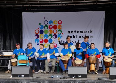 Trommelgruppe trommelt gemeinsam auf einer Bühne.