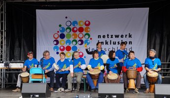 Trommelgruppe trommelt gemeinsam auf einer Bühne.