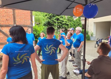 Personen mit tragenden T-Shirts der "Grünen Bananen" stehen draußen auf einem Hof.