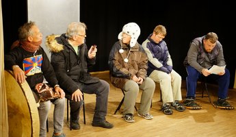 Fünf Männer sitzen in einer Reihe und tragen Winterjacken.