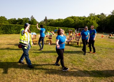 Personen gehen lachend durch die Wiese.