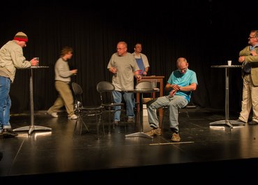 Mehrere Personen stehen vereinzelt an eigenen Stehtischen.