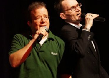 Zwei Personen singen gemeinsam am Mikrofon.