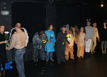 Darsteller stehen in einer Reihe auf der Bühne und erhalten Blumen.