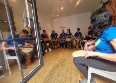 Trommelgruppe spielt gemeinsam und bildet einen Halbkreis in einem Raum.