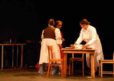 Drei Damen räumen den Esstisch auf.